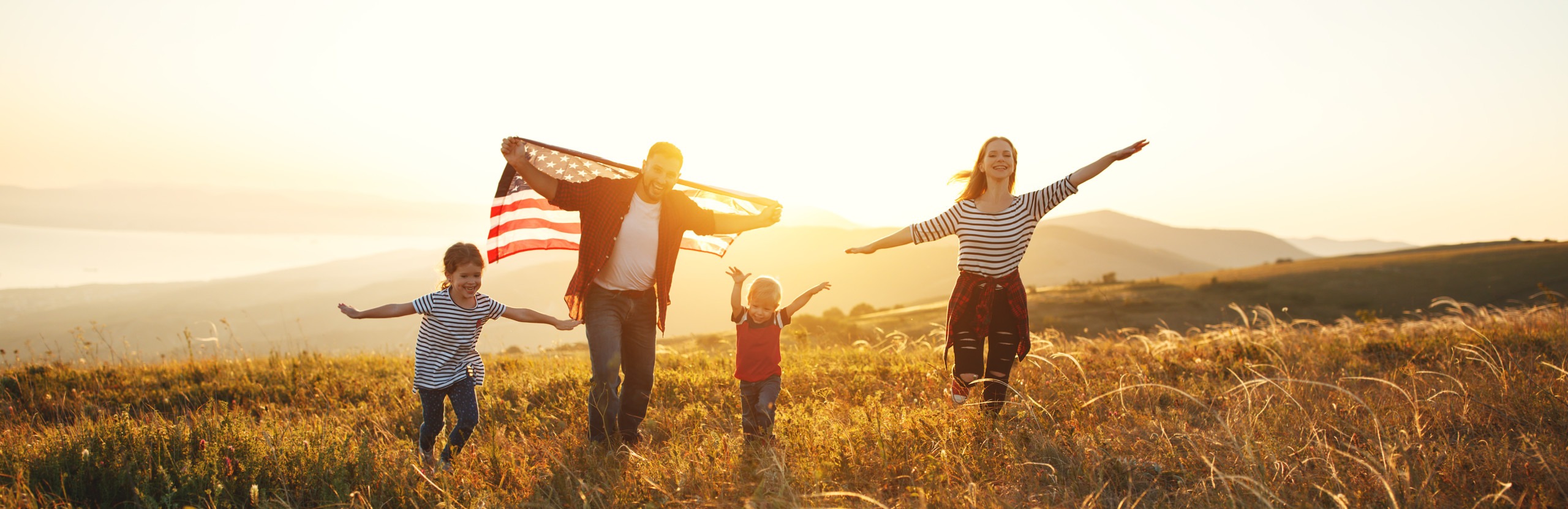 family in field with sunshine and flag
