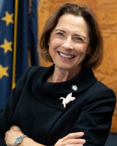 professional woman smiling at camera with Alaska flag in background