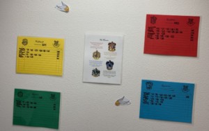 4 colored papers hung on a wall with name son them, representing the 4 houses of Hogwarts in Harry Potter